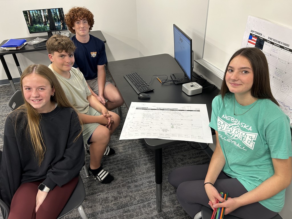 Picture of students looking at camera with paper calendar in between them.