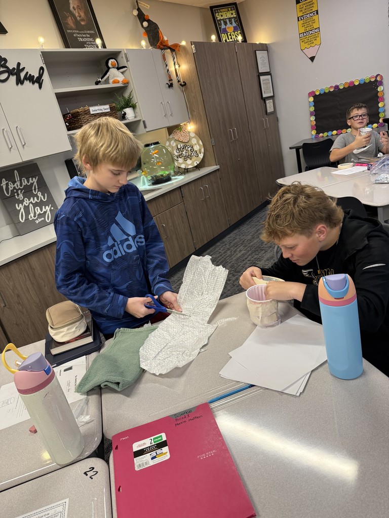 Students at desks working on cups. 