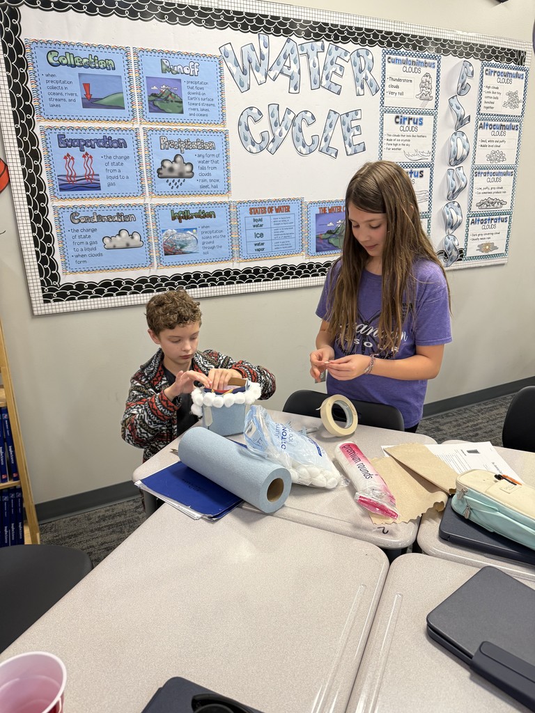 Students working at tables creating cups. 