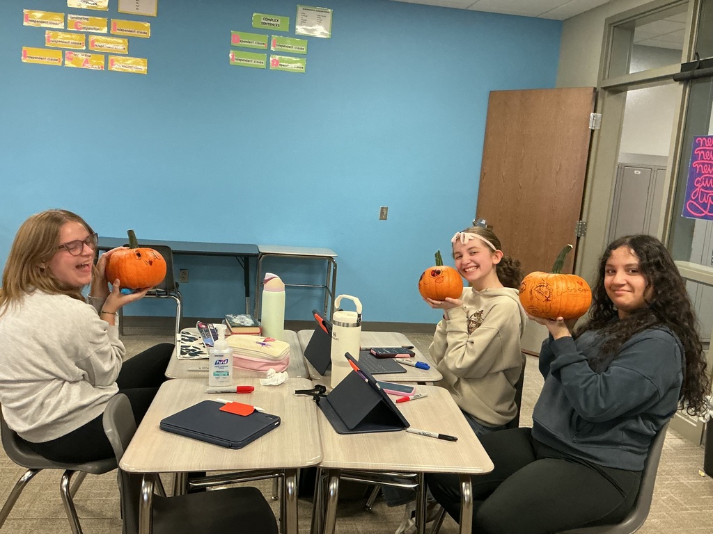 Photo of three students smiling and posing with their pumpkins.