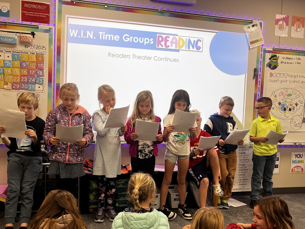 students reading a story to their class in readers theatre