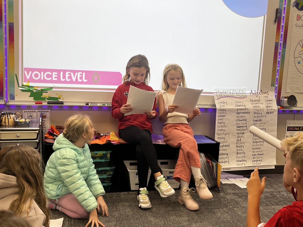 students reading a story to their class in readers theatre