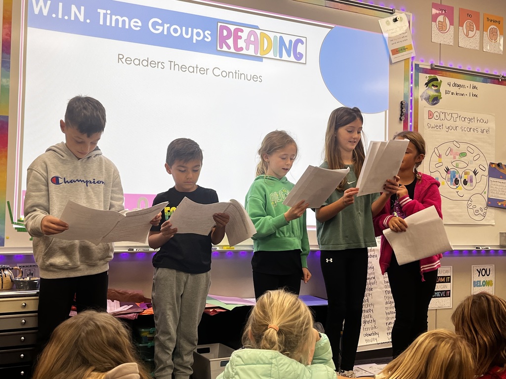 students reading a story to their class in readers theatre