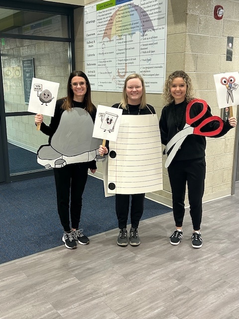 Photo of three teachers dressed up as a rock, paper, and scissors.