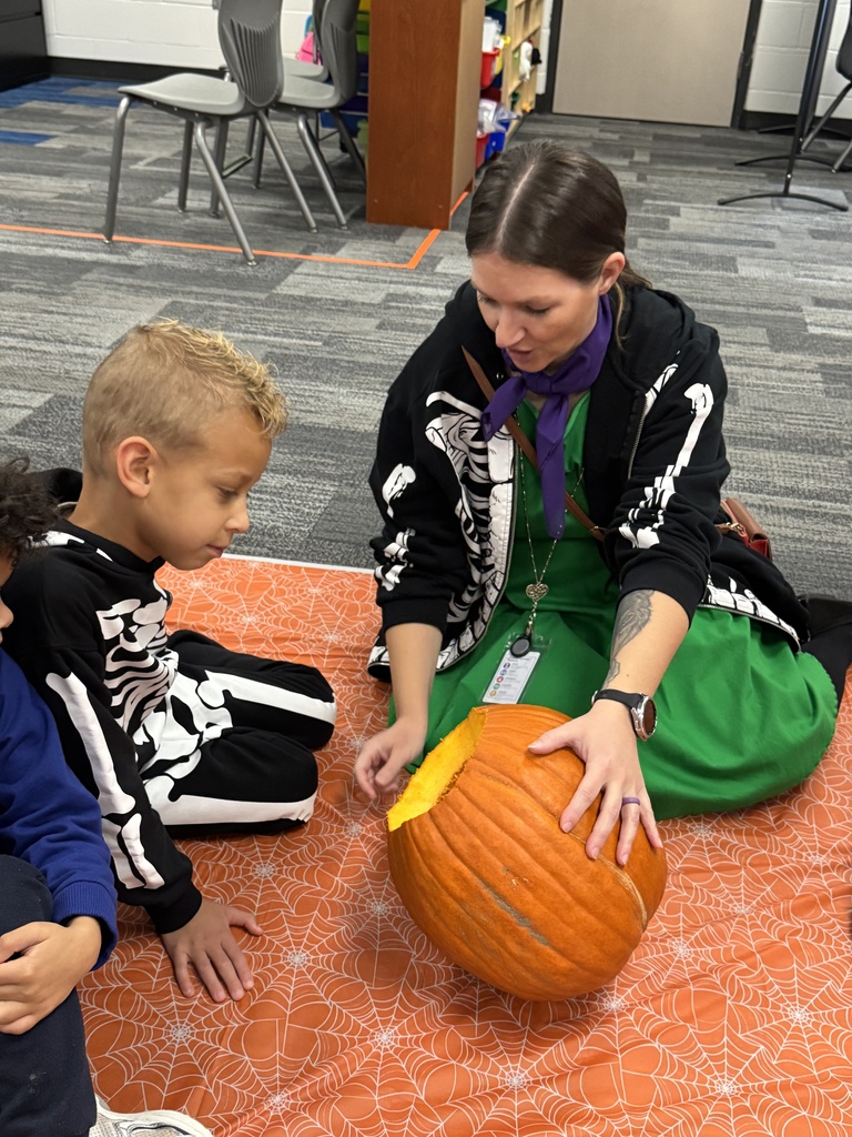 A student and para look inside a pumpkin.