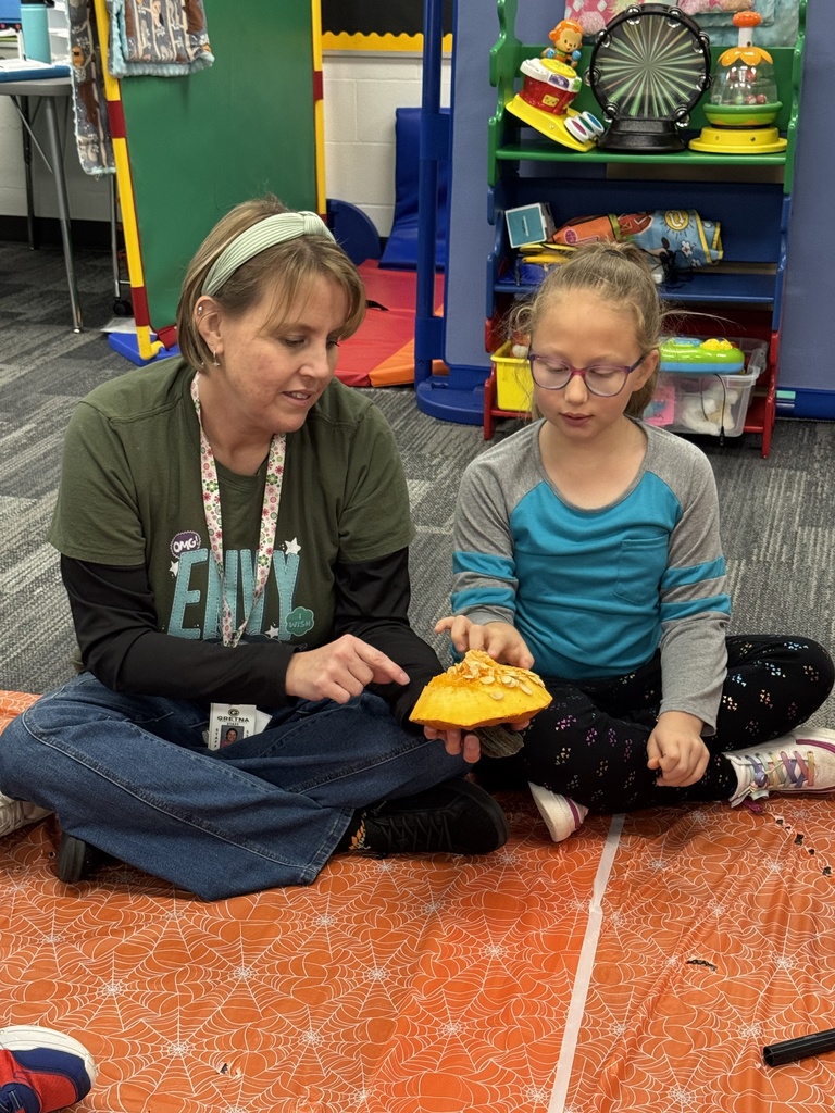 A para and student touch the inside of the pumpkin lid.