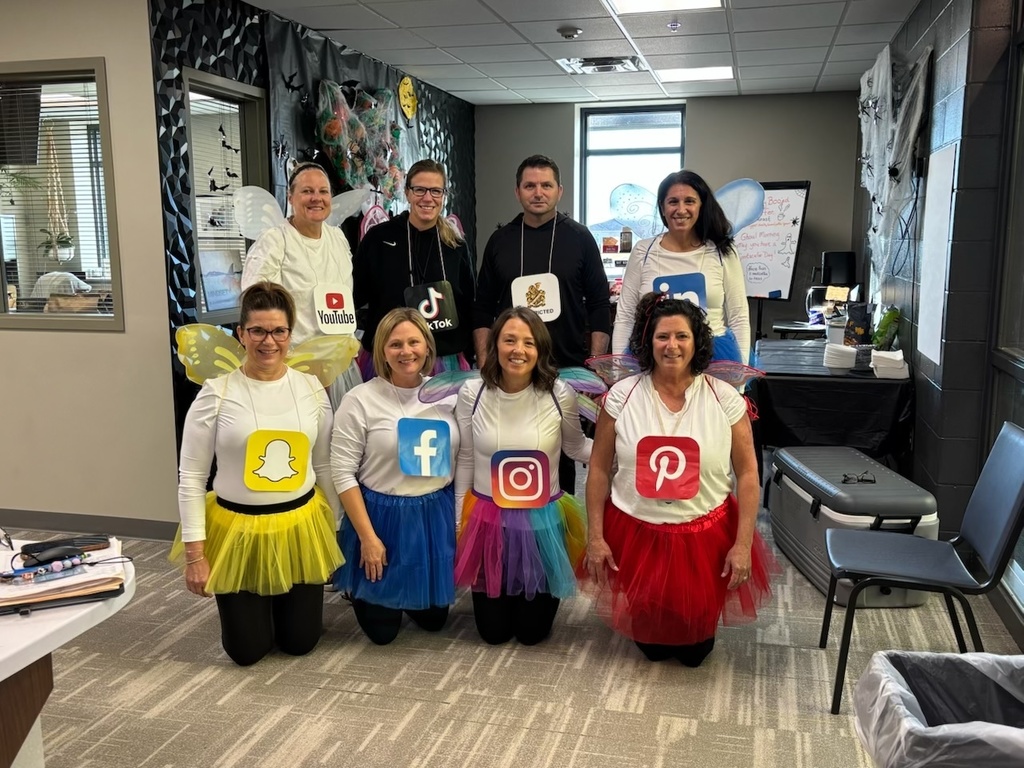 Photo of office staff wearing tutus and wings with social media signs around their necks.