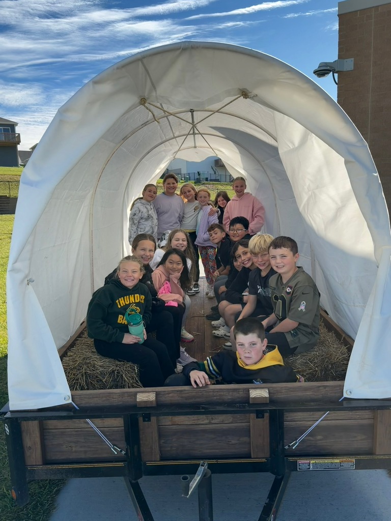 students smiling for a photo in a covered wagon