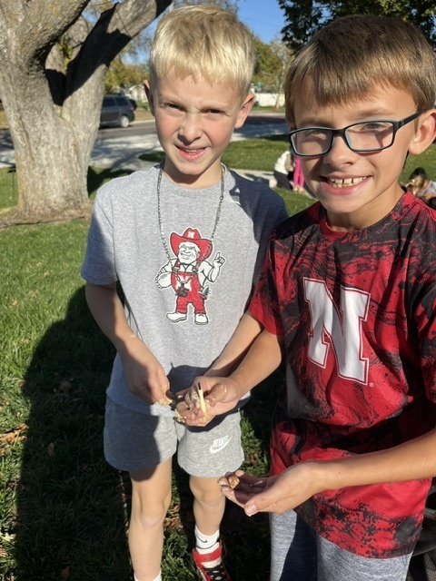 Two boys standing outside next to a tree with sand in their hands.