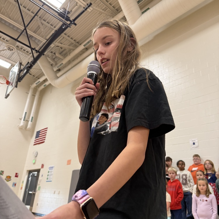 A fifth grade girl shares her essay in front of the school  