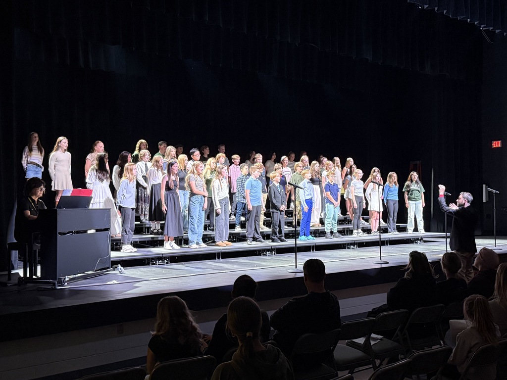 Photo of choir students standing on risers and singing.