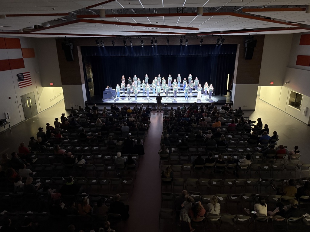 Photo from a distance showing choir students performing on stage.