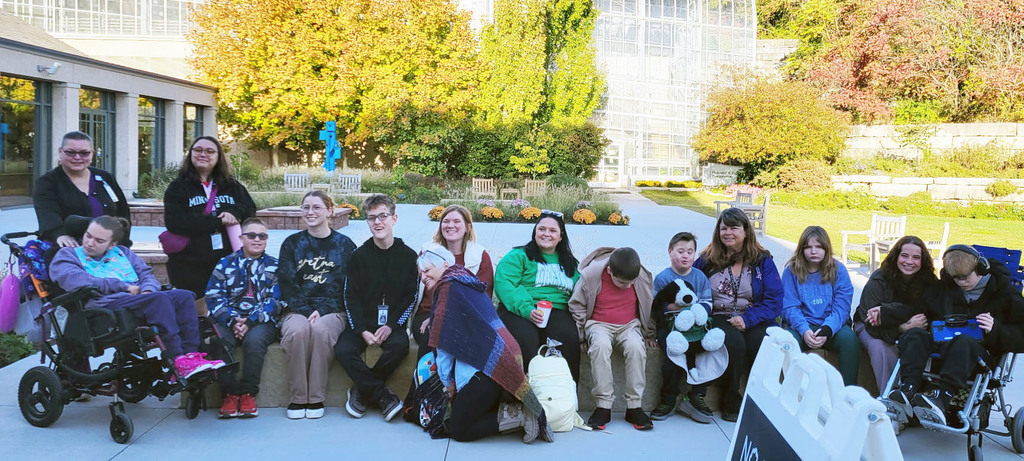 a large group of students sitting outside in the gardens
