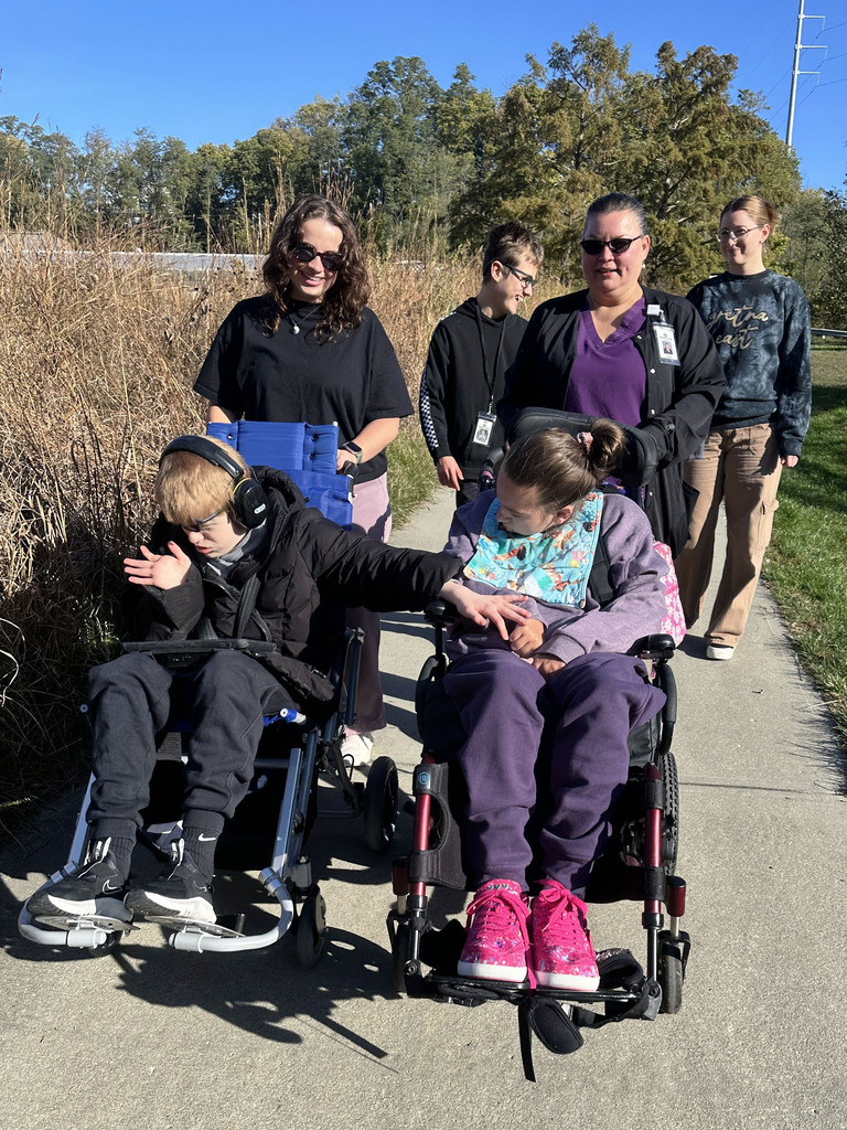 students and teachers walking down a paved sidewalk in the gardens