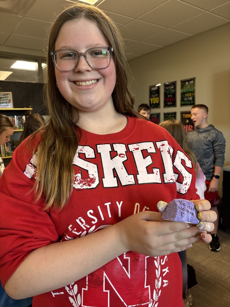 Photo of a student holding a rock with "You are wanted" painted on it.