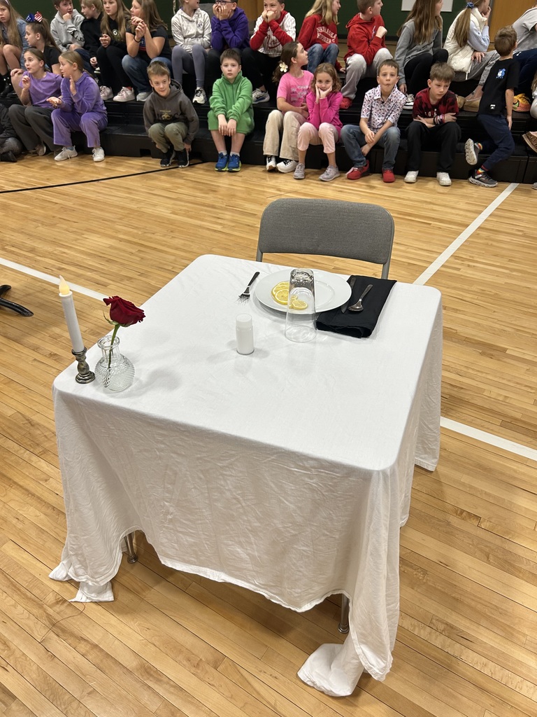 Chair seated a table with a white tablecloth with a plate and drink and silverware set out.
