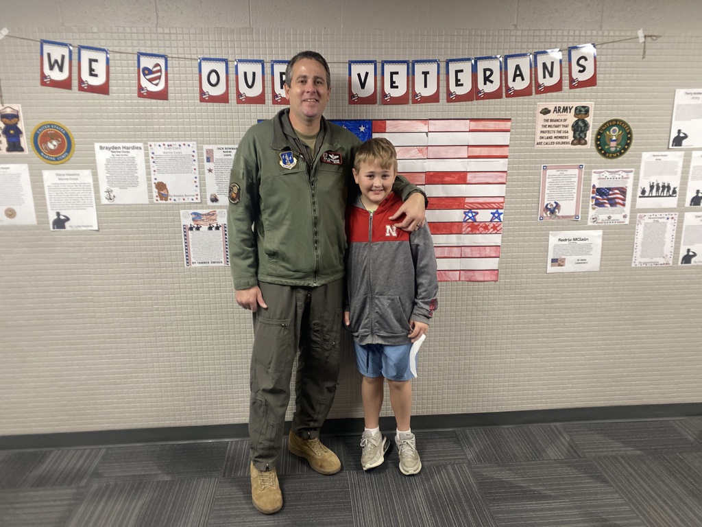 Student and his dad standing in front of a sign that says We Love Our Veterans