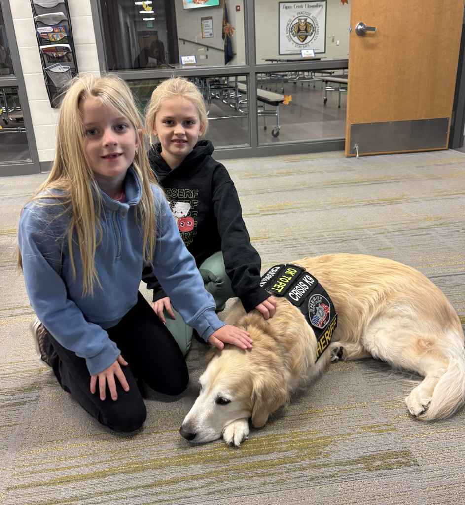 Two students petting Henry, the therapy dog.