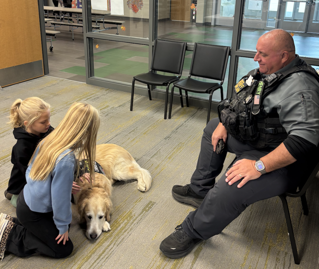 Two girls petting Henry, the therapy dog.