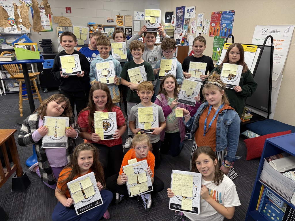 Group of kids holding up folders with sticky notes of things they are grateful for on the sticky notes.