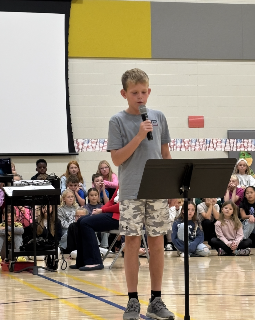 Student reading his Veterans Day Essay during a school assembly.