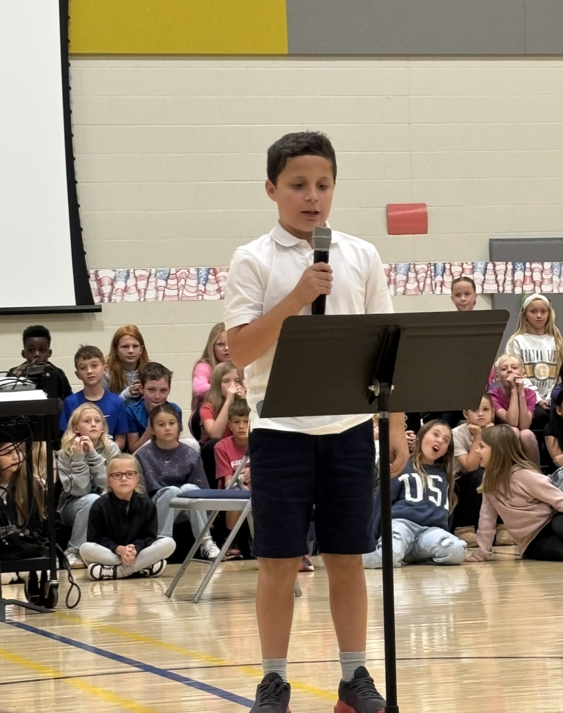 Student reading his Veterans Day Essay during a school assembly.
