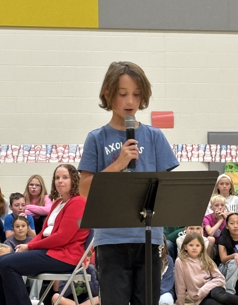Student reading his Veterans Day Essay during a school assembly.