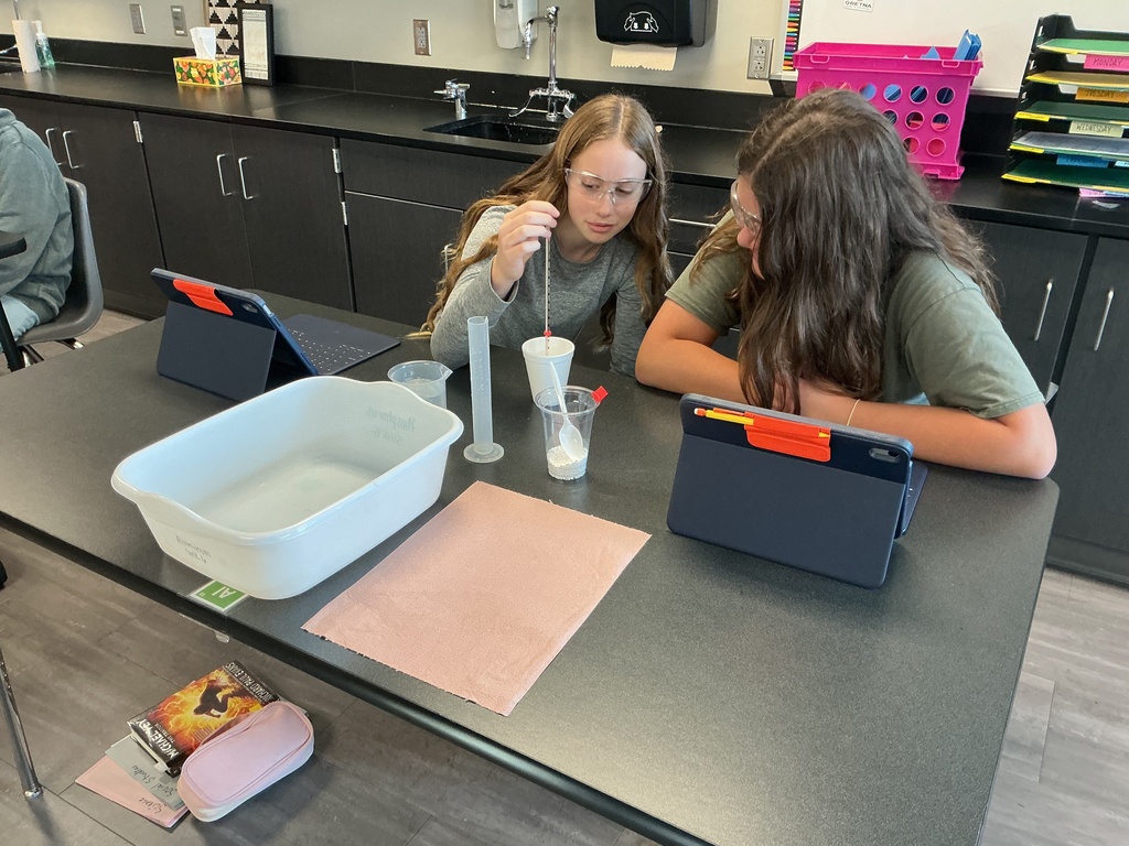 Photo of two students measuring water for their lab experiement.
