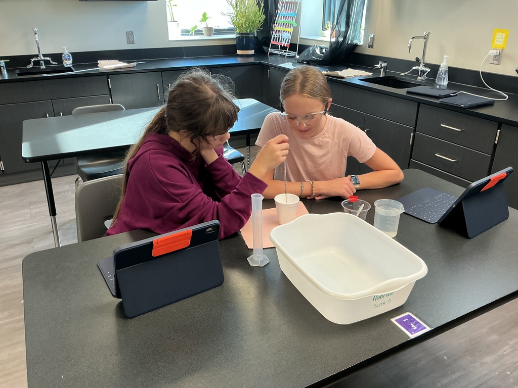 Photo of two students measuring water for their lab experiement.