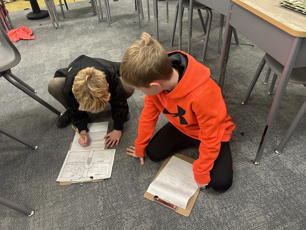 students work on a project on the floor of a classroom