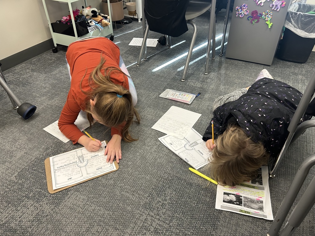 students work on a project on the floor of a classroom