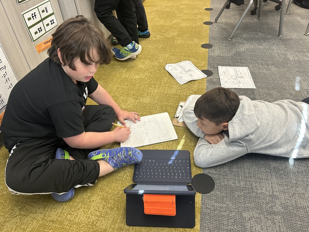 students work on a project on the floor of a classroom