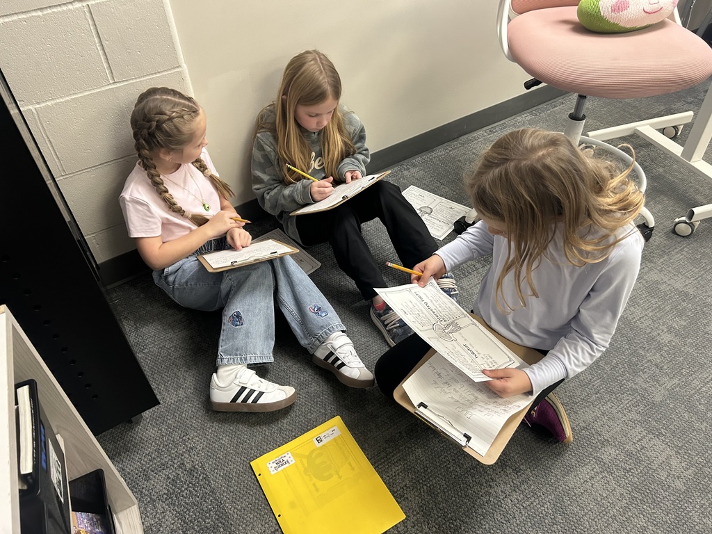 students work on a project on the floor of a classroom