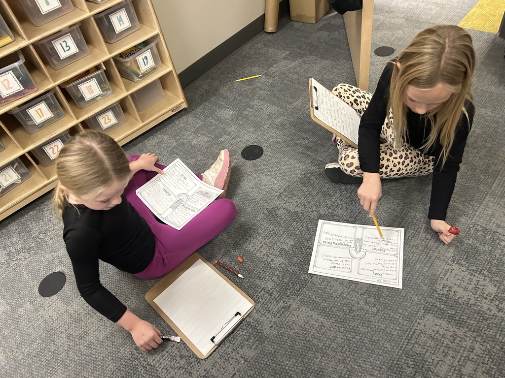 students work on a project on the floor of a classroom