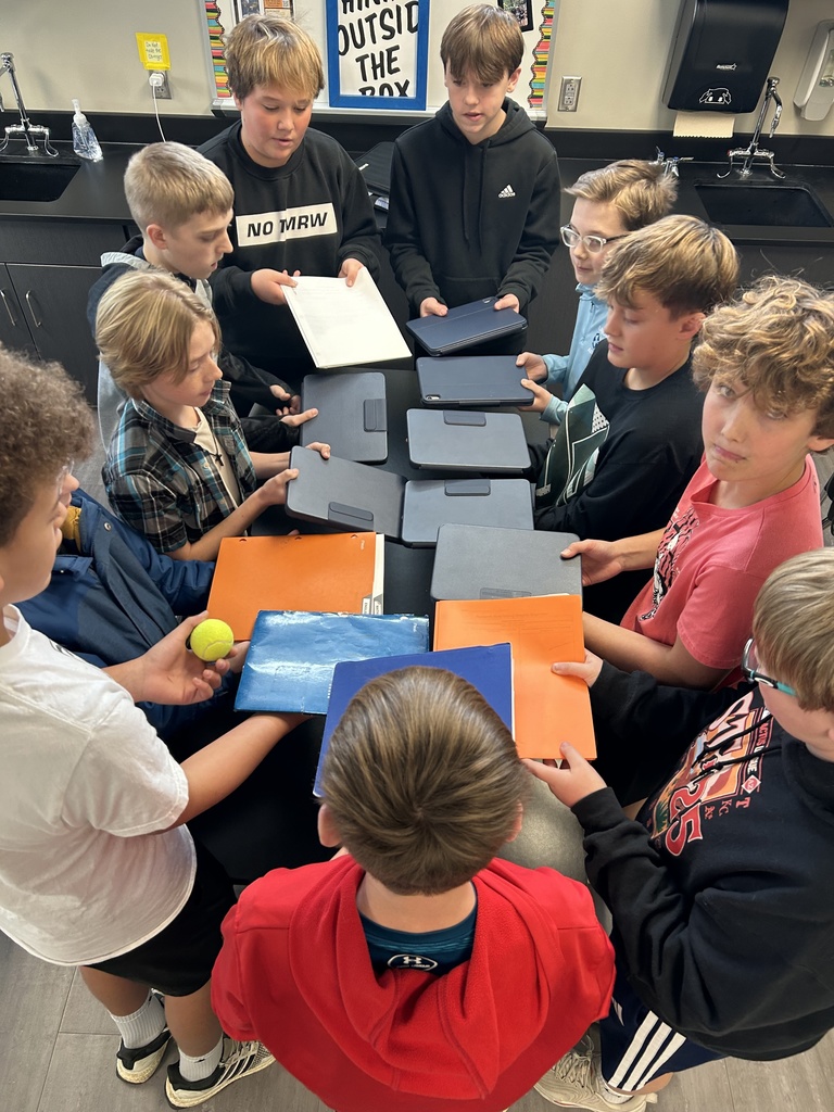 Photo of students in a circle using the backs of their iPads for the tennis ball challenge.