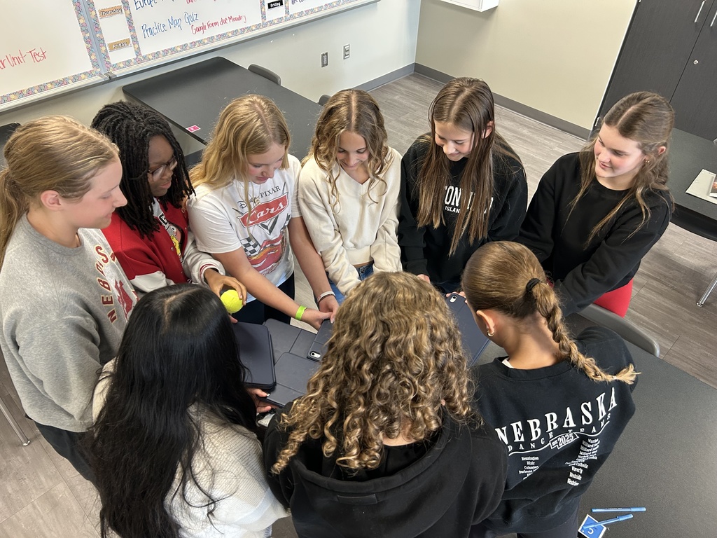 Photo of students in a circle using the backs of their iPads for the tennis ball challenge.