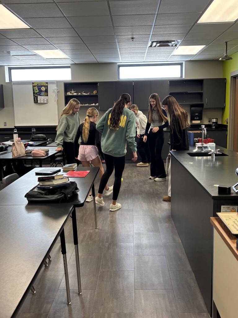Photo of students in a circle trying to kick a tennis ball.
