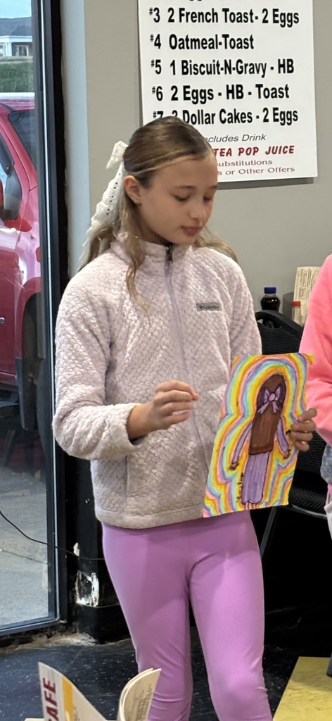 student holding their artwork of a girl facing the away from audience
