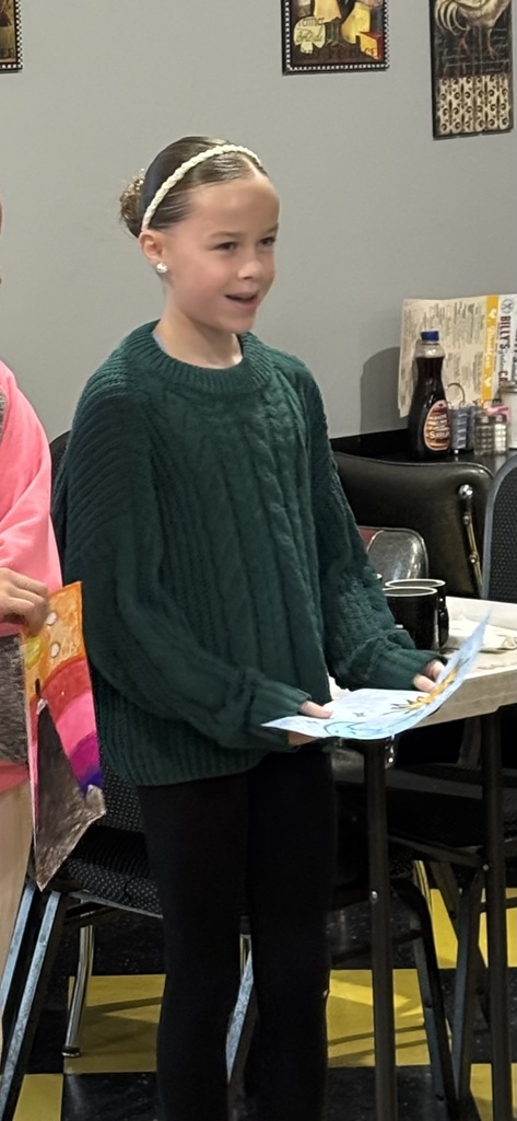 student holding their artwork talking about it with the Optimist Club