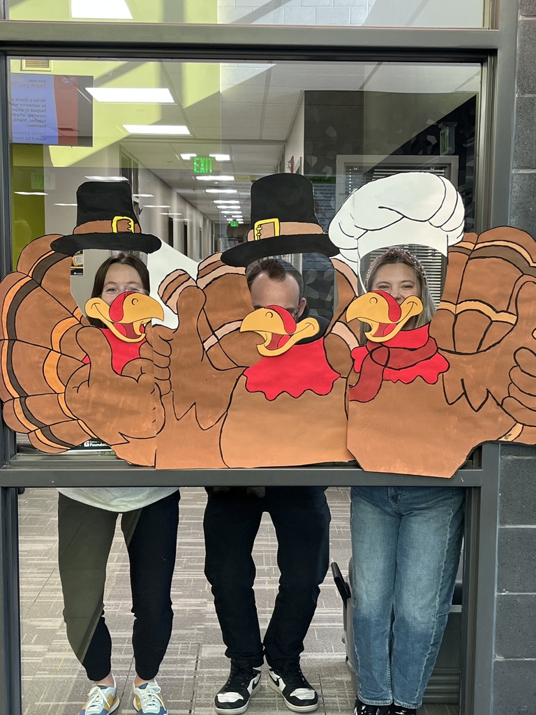 Photo of a painting of three turkeys with circles cut out where their eyes would go. Three teachers placed their heads in those circles to make it look like they are the turkeys.