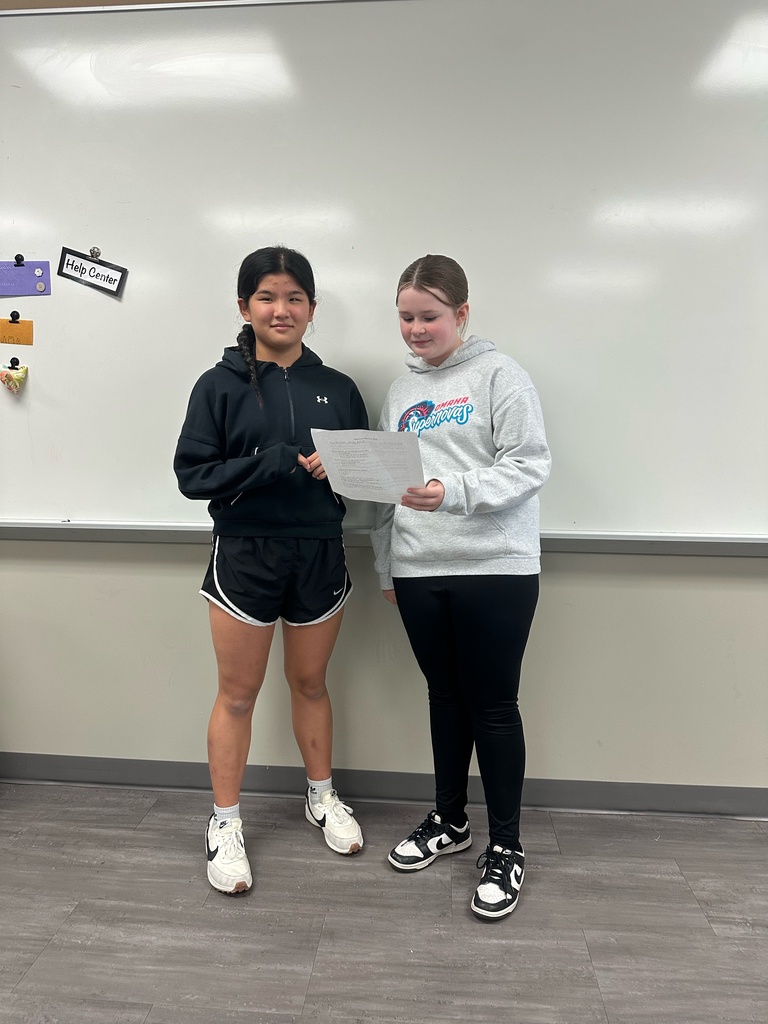 Photo of two students standing and holding a paper as they perform their nutrient rap.