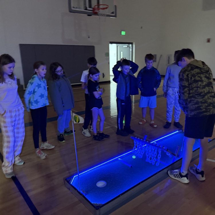 students watching a classmate hit a ball on a glow golf hole  