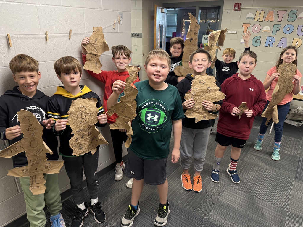 Group of boys holding designs made out of paper bags with drawings on them that resemble buffalo hides.