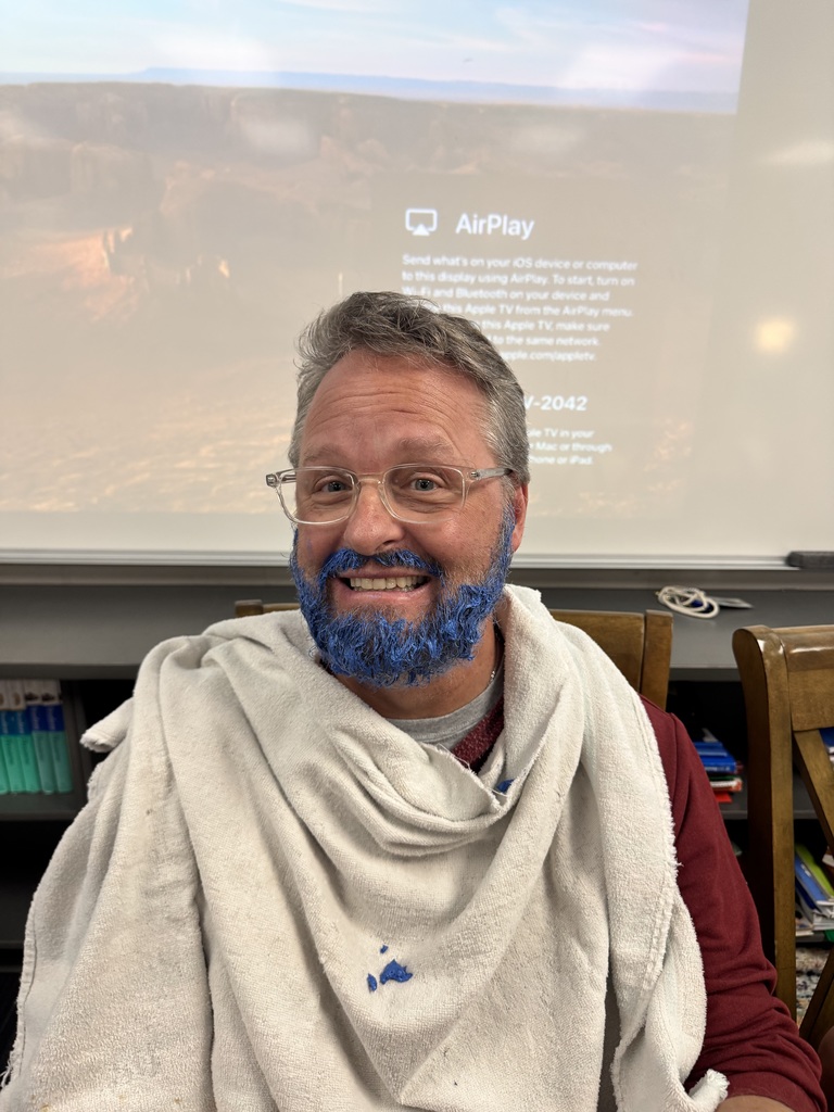 Man smiling wearing glasses while sporting a blue beard.