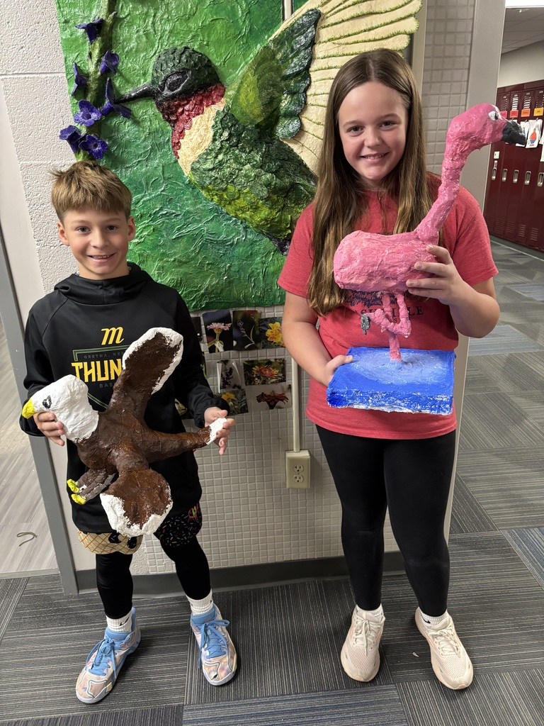 A boy holding an eagle created out of plaster and a girl holding an ostrich created out of plaster.
