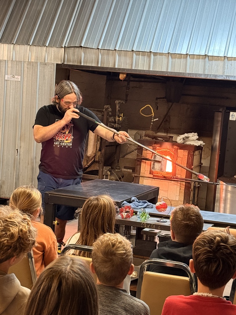 5th graders learning about hot shops on their field trip. Person blowing glass.