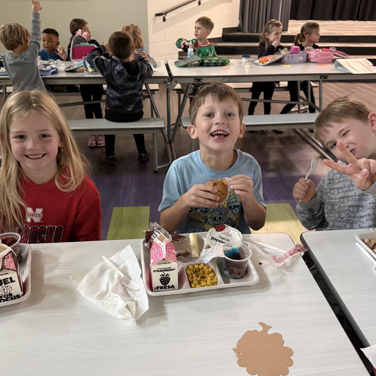 3 kindergarten students smiling with their thanksgiving meal