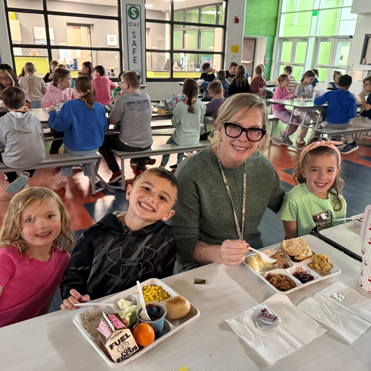 3 kindergartners and their teacher enjoy the thanksgiving feast