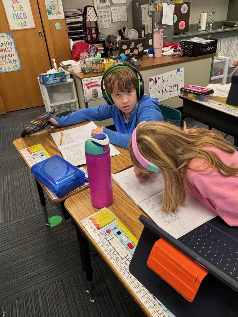 Group of 2nd graders sitting at their desks working with their headphones on and working on their iPads.