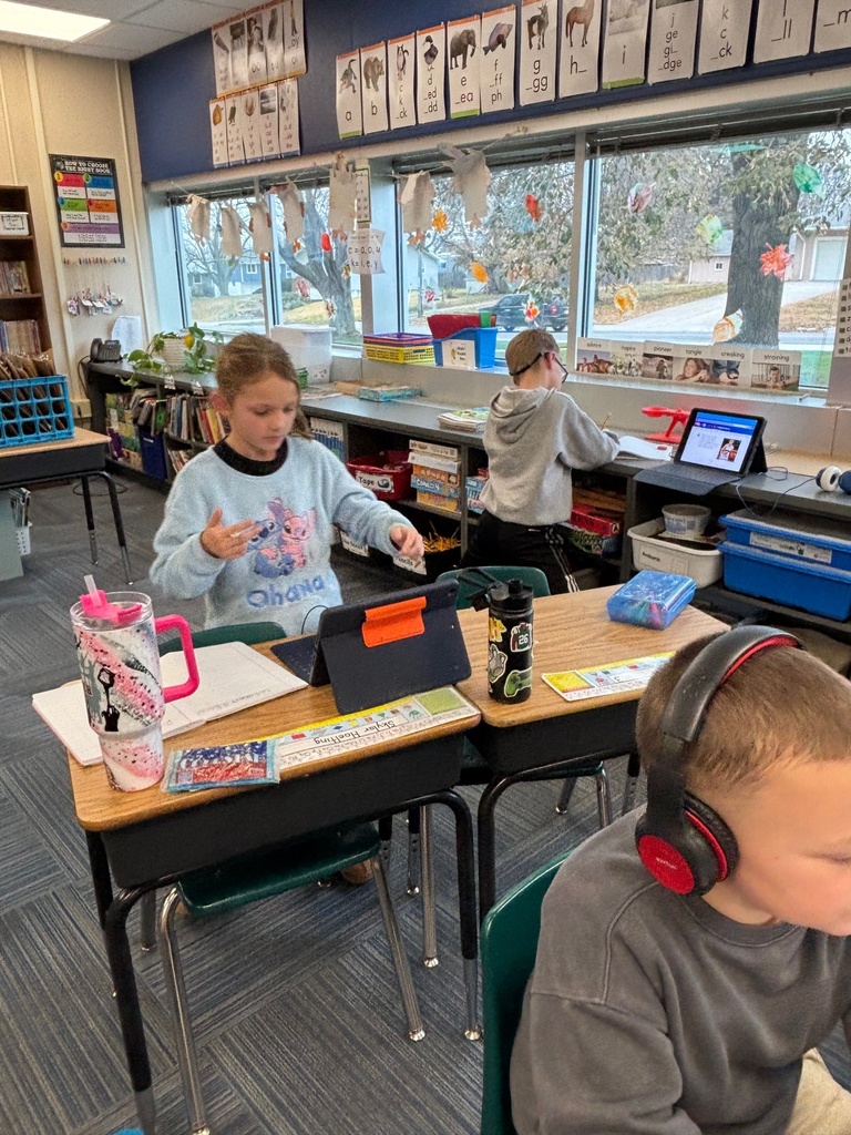 Group of 2nd graders sitting at their desks working with their headphones on and working on their iPads.